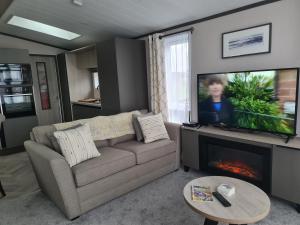 a living room with a couch and a flat screen tv at Mawgan Pads Perranporth in Cubert