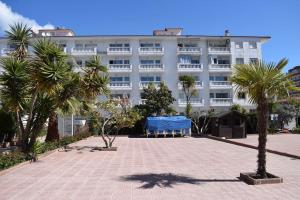 un gran edificio blanco con palmeras delante en Alegre apto con piscina, a 300m de la playa., en Blanes