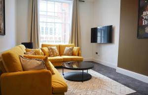 a living room with a yellow couch and a tv at Berry's Retreat - Kist Accommodates in Knaresborough