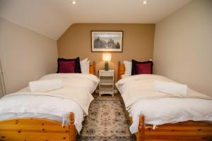 two beds in a room with white sheets and red pillows at Thatchers Cottage - Rudge Farm Cottages in Bridport