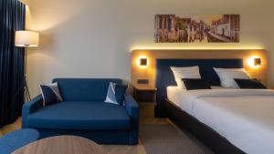 a bedroom with a bed and a blue chair at Gresham Belson Hotel Brussels in Brussels