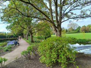 a park with a bench and a river and trees at Charming 4-Bed Victorian House in Retford in Retford