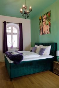 a bedroom with a large bed with a green headboard at Denkmalgeschützte große Boheme Altbauwohnung in Citylage in Landshut