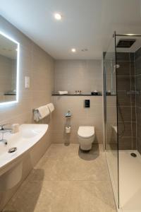 a bathroom with a toilet and a sink and a shower at Gresham Belson Hotel Brussels in Brussels