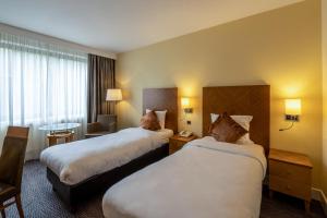a hotel room with two beds and a table at Gresham Belson Hotel Brussels in Brussels