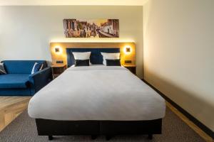 a bedroom with a large bed and a blue couch at Gresham Belson Hotel Brussels in Brussels