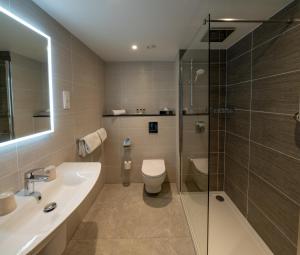 a bathroom with a sink and a toilet and a shower at Gresham Belson Hotel Brussels in Brussels