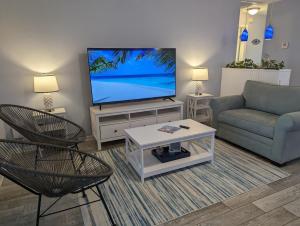 uma sala de estar com uma televisão e um sofá e cadeiras em Blue Flamingo - Pool, Sunsets, Dock, Lift, Direct Gulf Access! em Cape Coral