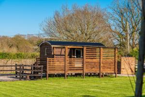 a wooden cabin with a table and chairs in a field at Hillside View Shepherds Hut - Ockeridge Rural Retreats in Little Witley