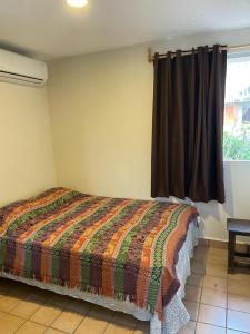 a bedroom with a bed with a colorful quilt and a window at Departamento centro de Boca del Río in Boca del Río