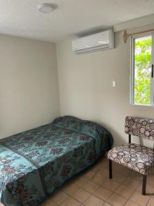 a bedroom with a bed and a chair and a window at Departamento centro de Boca del Río in Boca del Río