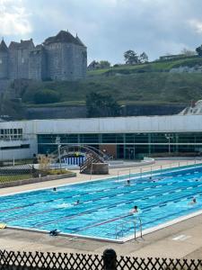 a large swimming pool with a castle in the background at Magnifique Appartement l'Aigrette in Dieppe