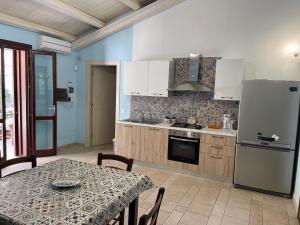 a kitchen with a table and a white refrigerator at Villa con piscina in San Vito lo Capo