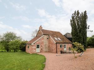 an old brick house with a grass yard at Old Farm Cottage in Upper Sapey