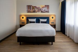 a bedroom with a large bed with a blue headboard at Gresham Belson Hotel Brussels in Brussels