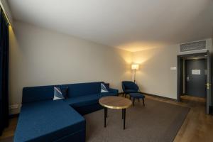 a living room with a blue couch and a table at Gresham Belson Hotel Brussels in Brussels