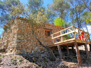 a stone house with a deck on a hill at Cabane des pachous in Tourves