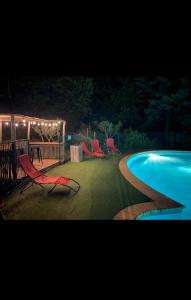 a group of chairs sitting around a swimming pool at night at Cabane des pachous in Tourves