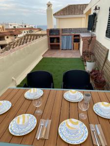 a wooden table with plates and wine glasses on a balcony at Ático duplex en Zahara de los Atunes in Zahara de los Atunes