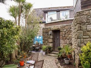 a stone house with a patio with chairs and plants at The Hexagon House in Penzance