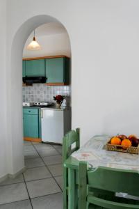 アギアアンナ・ナクソスにあるHOTEL KAPARIのキッチン(緑のキャビネット、フルーツ付きのテーブル付)