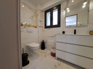 a white bathroom with a toilet and a sink at Maison au calme idéalement située proche plage in Bonifacio