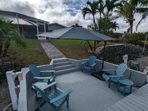 a patio with blue chairs and an umbrella at Blue Flamingo - Pool, Sunsets, Dock, Lift, Direct Gulf Access! in Cape Coral