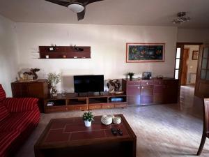 een woonkamer met een rode bank en een flatscreen-tv bij Casa Rural La Chistera in Avila