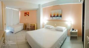 a bedroom with a large white bed and a table at Marsallis Praia JR 406 in Natal
