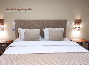 a bedroom with a large white bed with pillows at Kastel Jampa Hotel in João Pessoa