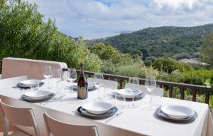 ein weißer Tisch mit Gläsern und einer Flasche Wein in der Unterkunft [PORTO CERVO]Incantevole Vista sul Golfo del Pevero in Abbiadori
