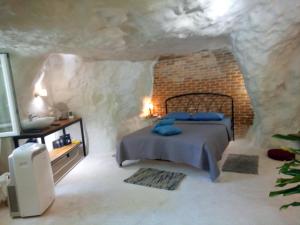 Cave house في مدينة هيراكيلون: غرفة نوم مع سرير في كهف حجري
