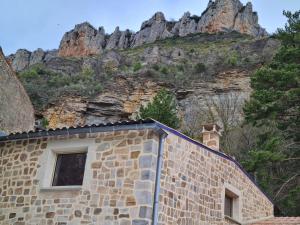 un bâtiment en pierre avec une montagne en arrière-plan dans l'établissement Gîte du Vallon des Sources, à Millau