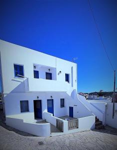 - un grand bâtiment blanc avec des portes et des escaliers bleus dans l'établissement Le stanze del tramonto di Eleni, à Lipsi