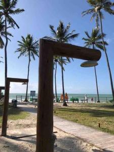 a wooden sign at a beach with palm trees at Flat Beira Mar - Carneiros Beach Resort in Tamandaré