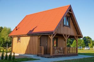 an orange roofed cabin with a porch at Dreamland skorupki in Ryn