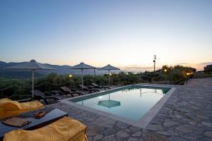 a swimming pool with chairs and umbrellas at dusk at Villa Aktis with Freshwater Pool and Sea View in Sissi