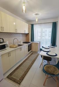 Select Apartment SIBIU في سيبيو: مطبخ مع دواليب بيضاء وطاولة مع كراسي