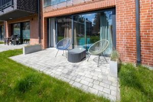 zwei Stühle und ein Tisch vor einem Gebäude in der Unterkunft Apartament Zakatek z ogrodkiem i miejscem w garazu podziemnym in Bielsko-Biała