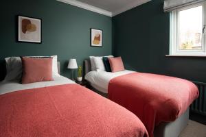 two beds in a room with green walls and red covers at Beautiful 5 Bedroom House - Alnwick in Alnwick