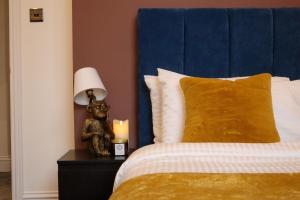 a bed with a blue headboard and a lamp on a night stand at The Knaresborough Retreat in Knaresborough