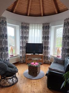 a living room with a flat screen tv and two windows at Jenny's Ferienwohnung in Monschau