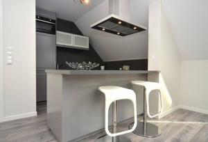 a kitchen with two white stools at a counter at Modern apartment 7 min to center in Bergen