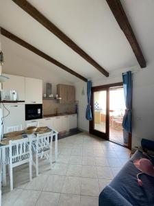 une cuisine avec une table blanche et une table dans l'établissement Isola Rossa La Paduledda Appartamento vista mare Il Mirto, à Cascabraga