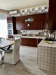 a kitchen with wooden cabinets and a table with a chair at Villa Porto Selvaggio in Santa Caterina di Nardò