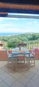 une table et des chaises sur un balcon avec vue dans l'établissement Isola Rossa La Paduledda Appartamento vista mare Il Mirto, à Cascabraga
