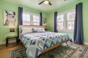 a bedroom with a bed with green walls and windows at Pastel Palace - near Plaza & Uptown 23rd in Oklahoma City