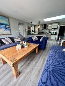 uma sala de estar com um sofá azul e uma mesa de madeira em Sandy feet retreat em Exmouth