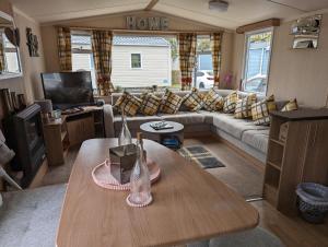a living room with a couch and a table at Haggerston Castle 3 Bedroom Deluxe Holiday Home in Cheswick