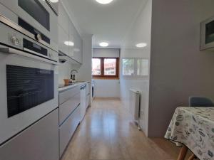 a kitchen with white appliances and a table and a tableablish at Magnífico apartamento en el corazón de La Toja in Isla de la Toja